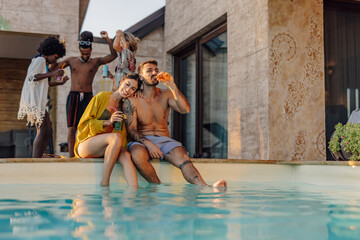 Happy couple relaxing by the pool with refreshing drinks at a summer party