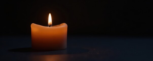 Simple candle against a dark background with soft light illumination, still life, darkness