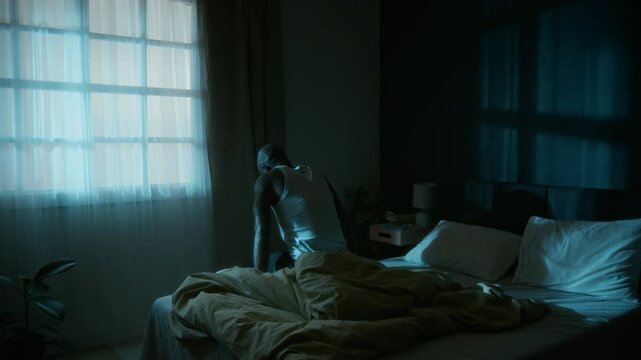 African American man standing up from his bed and sleepwalking around his bedroom early in morning