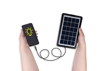 Portable solar panel in one hand connected to smartphone in other hand on transparent background (close-up). Smartphone screen shows light bulb icon. Alternative energy concept