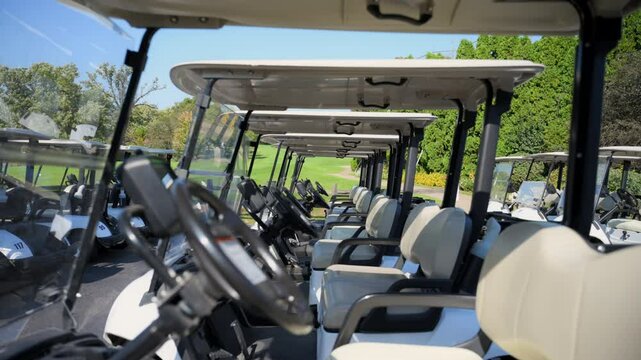 Close view of Golf carts parked in the designated area at a golf club. Neatly arranged electric vehicles ready for players to use on the course. Camera slowly moves through the parked carts