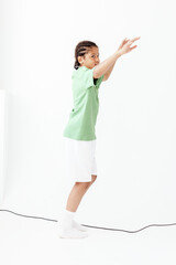 Young boy in green tshirt and white shorts reaching for trendy skateboard in urban skate park