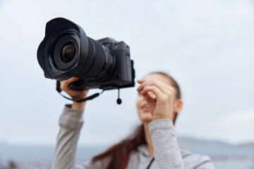 Young woman with a camera smiles outdoors, capturing moments, showcasing enthusiasm for...
