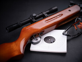 Air gun, shield and goggles on a dark background.