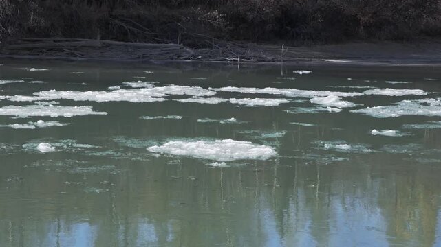 Drifting ice on broad river. Melting blocks quickly float on the water on sunny day. Chuya, Altai
