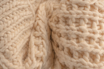A fragment of beige knitted fabric, knitted from white sheep wool.