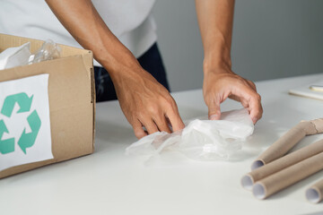Person sorting plastic waste and recycling materials in an organized workspace, promoting...