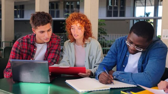 Three enthusiastic students collaborating together on academic projects while sharing ideas and discussing important concepts during their study session at a university campus in a friendly meeting