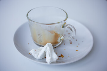 Empty coffee cup and crumpled napkin on white plate