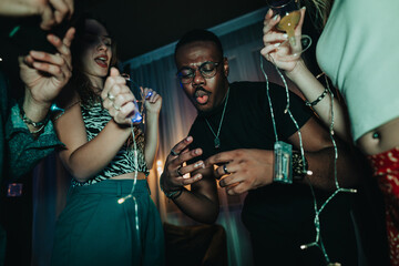 Group of friends celebrating with music, drinks, and vibrant lights at a party