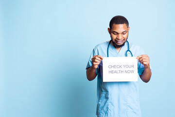Portrait of african american guy presenting a message on a paper, urging patients to do a medical...