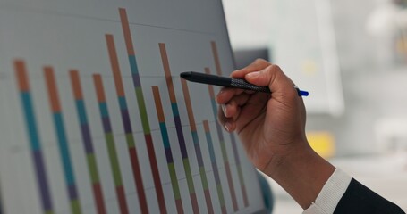 Close-up of computer monitor bar graph displayed dark-skinned man's hand holding pen touche screen...