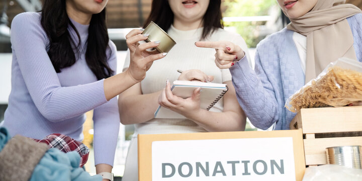 Diverse women discussing donation items and organizing contributions for community service project.