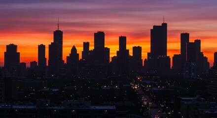 Fototapeta premium Cityscape Silhouette at Sunset: A dramatic skyline silhouette of a modern city is set against a vibrant, fiery sunset sky.