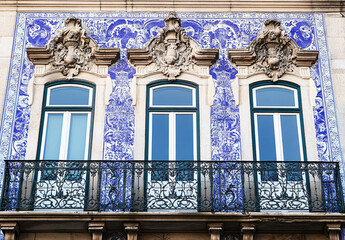 Traditional Portuguese building facade with azulejo tiles, balcony, and vibrant colors.