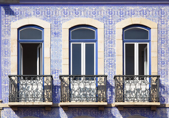 Traditional Portuguese building facade with azulejo tiles, balcony, and vibrant colors.