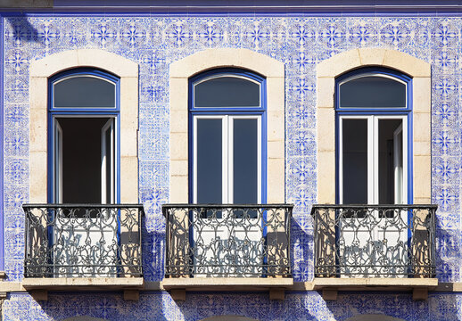Traditional Portuguese building facade with azulejo tiles, balcony, and vibrant colors. - Powered by Adobe
