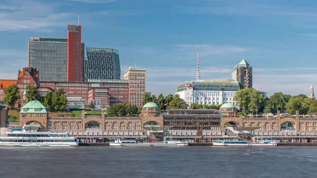 Skyline timelapse of St. Pauli Piers (Landungsbrucken) with ferries in Hamburg, Germany. Iconic clock tower, ships docked in the marina and panoramic views of the harbor under a cloudy blue sky