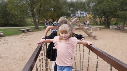 Obraz premium A joyful child plays excitedly on a colorful bridge at a park with cheerful friends, creating beautiful memories