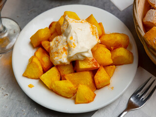 Traditional Spanish fried potatoes Patatas bravas served with cheese sauce and spicy sauce with paprika and chili