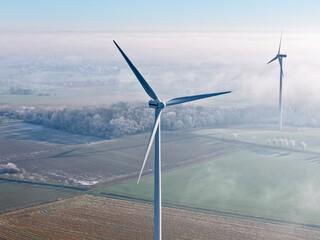 Aerial view of a wind turbine in a winter landscape with sun and deep fog over the fields, wind energy, renewable energies, energy transition, climate protection