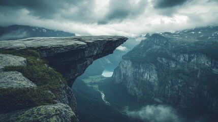 A dramatic overhang on a mountain cliff, looking down into a deep valley, moody lighting and copy space.
