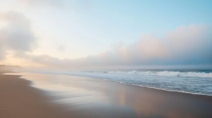 Obraz premium A foggy beach morning with soft mist hovering over smooth wet sand and gentle waves.