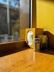 White paper napkin holder with pepper and salt near the window in a cafe