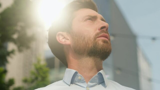 Close-up middle-aged 40s male employer investment entrepreneur adult Caucasian bearded man business guy businessman serious calm peace in city portrait sun outdoors looking at sky thinking job startup