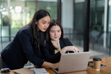 Diverse businesswomen collaborating on project analysis and planning in a modern office setting.