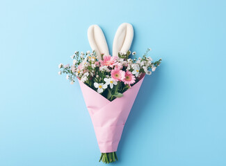 Easter bouquet with bunny ears and flowers in a pink paper wrap against a pastel blue background. Advertisement for florists.Minimal creative easter holiday concept.Copy space,flat lay 
