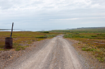 Gravel road along the Barents Sea shore in tundra at sunset. Rybachy Peninsula, Murmansk region,...