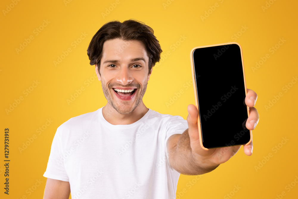 Poster Mobile Application Ad. Portrait Of Excited Man Showing Smart Phone Black Empty Screen Recommending App Standing Over Yellow Orange Studio Background. Cellphone Display Mock Up, Check This Website