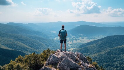 Contemplative hiker stands atop rocky outcrop gazing over panoramic mountain expanse under clouded skies