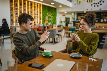 boyfriend use mobile phone to take a photo of his girlfriend at cafe