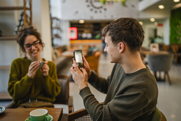 boyfriend use mobile phone to take a photo of his girlfriend at cafe