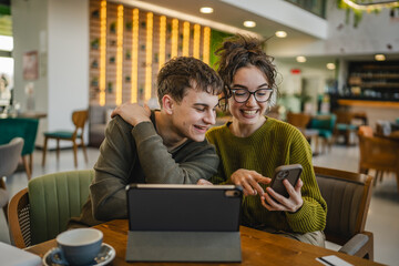 couple explore internet on mobile phone and digital tablet at cafe