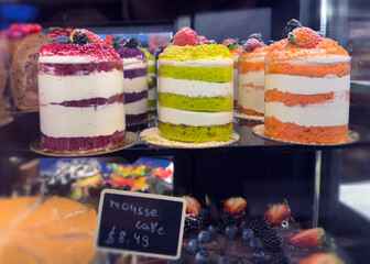 Vibrant Mousse Cakes Display with Layers of Whipped Cream and Fresh Berry Garnish in a Bakery Showcase