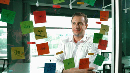 Portrait of professional businessman analysis marketing idea on sticky notes. Smiling caucasian...
