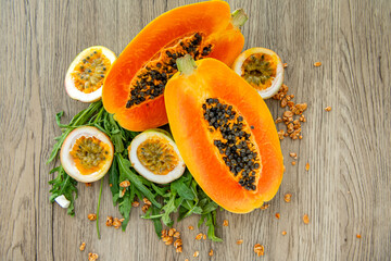 Papaya fruit, passion fruit, rucola and granola on a light wooden background. Slices of sweet...