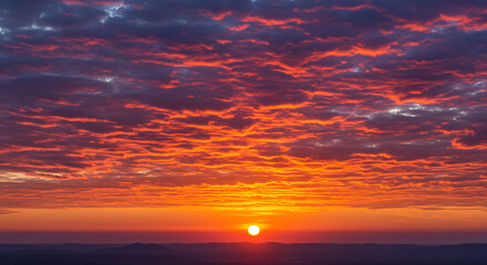 Fiery orange and pink clouds at sunset stretching across the sky.