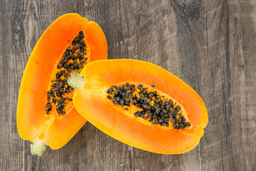 Papaya fruit on a dark wooden background. Slices of sweet papaya on wooden background, Halved papayas, copy space for text