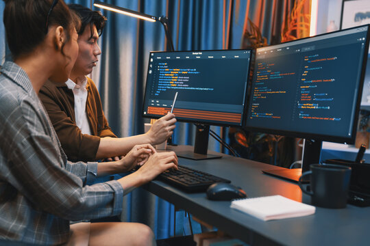 IT developers discussing with point to intelligent website development coder system running data online two screens information technology at neon light room at modern office. Infobahn.