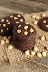 Tasty chocolate cookies with hazelnuts on wooden table, closeup