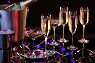 Champagne in glasses, bottle and ice buckets on black mirror surface
