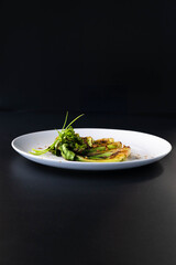 Bok choy is elegantly arranged on a white plate, showcasing vibrant greens against a dark setting.