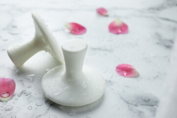 Wet spa stones and petals on white marble table, closeup. Space for text