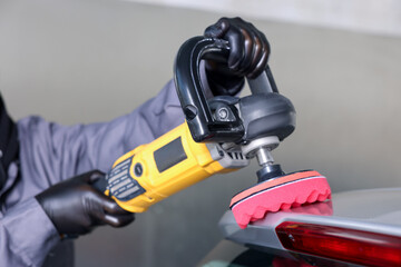 Man polishing car with orbital polisher indoors, closeup