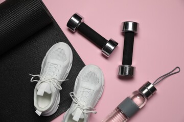Dumbbells, water bottle, fitness mat and sneakers on pink background, flat lay