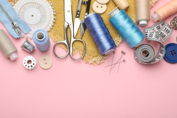 Different sewing supplies on pink background, flat lay. Space for text